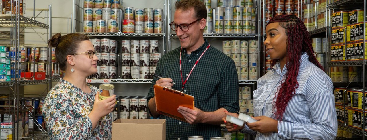 three people have a conversation inside a food pantry