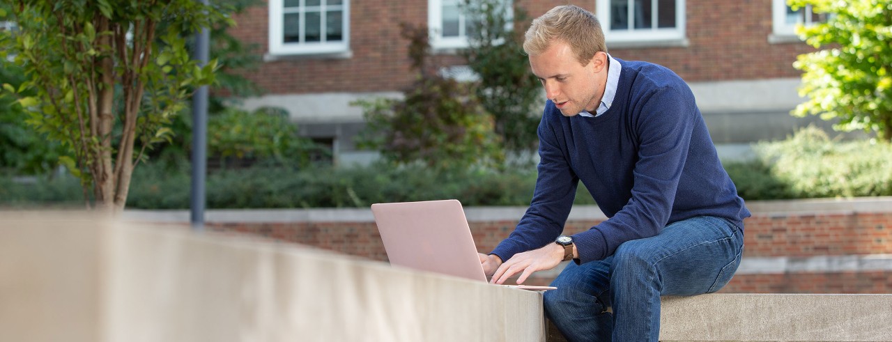 man outside works on a laptop