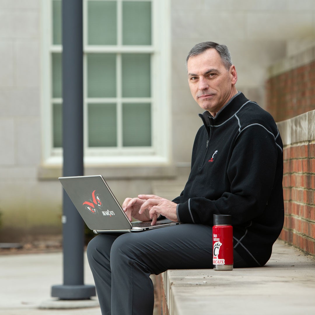man sits outside with a laptop and water bottle